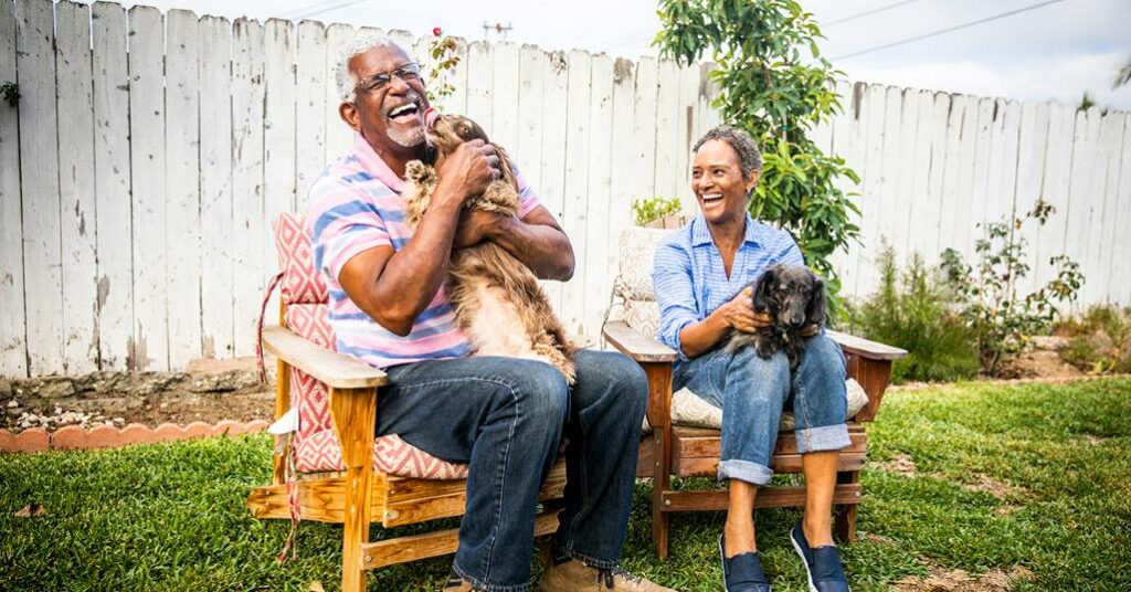Senior couple sitting in chairs holding two dogs
