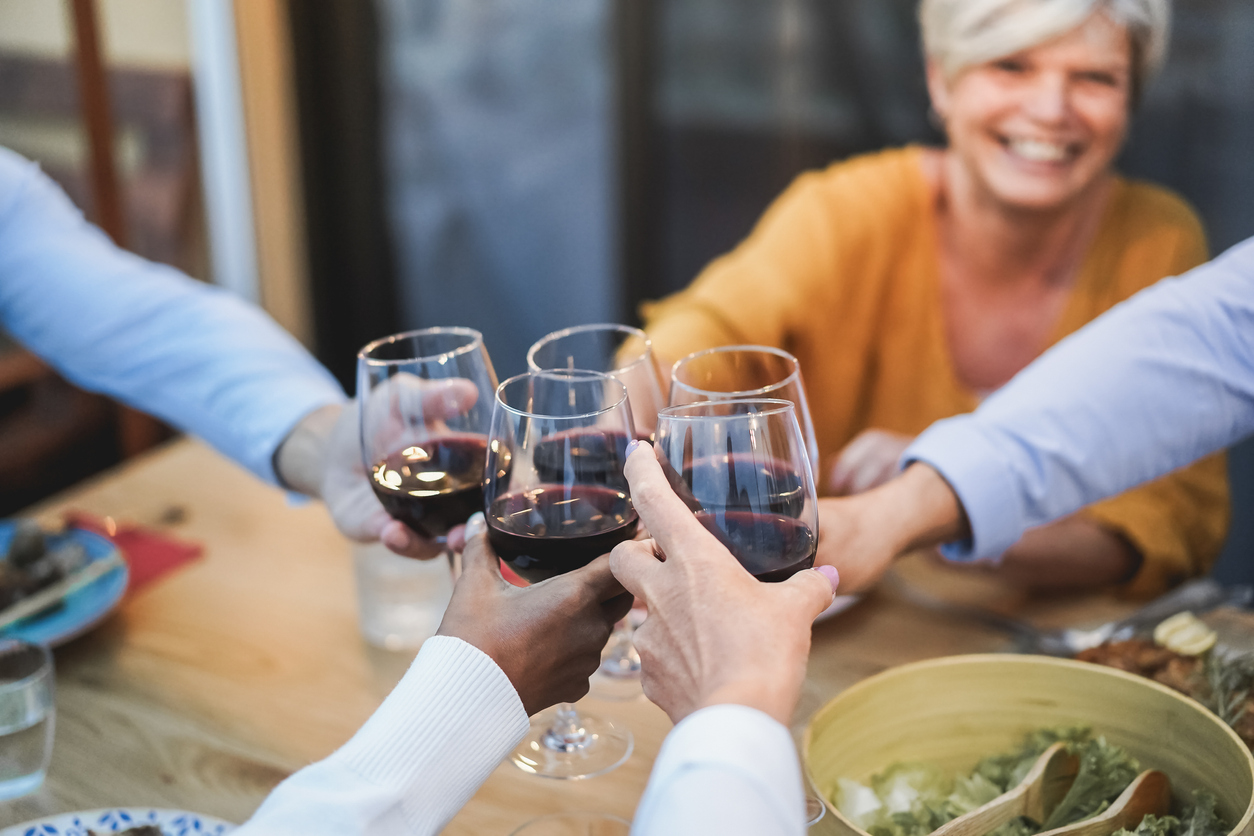 Senior people having fun cheering with wine at patio dinner - Focus on female face