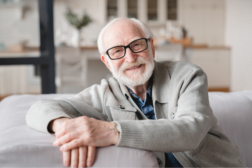 senior man sitting on couch posing for a photo