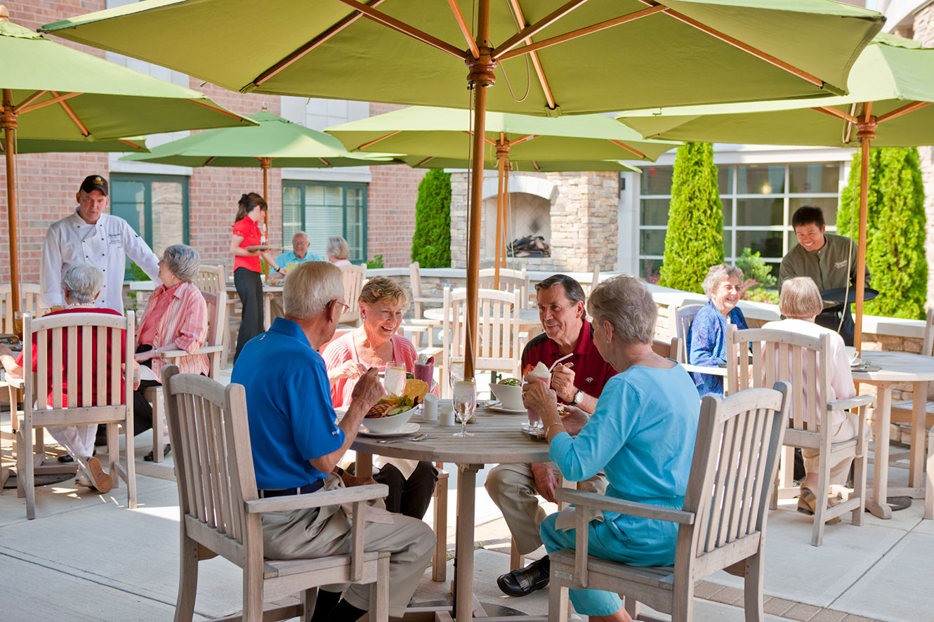 seniors sitting at a table under an umbrella