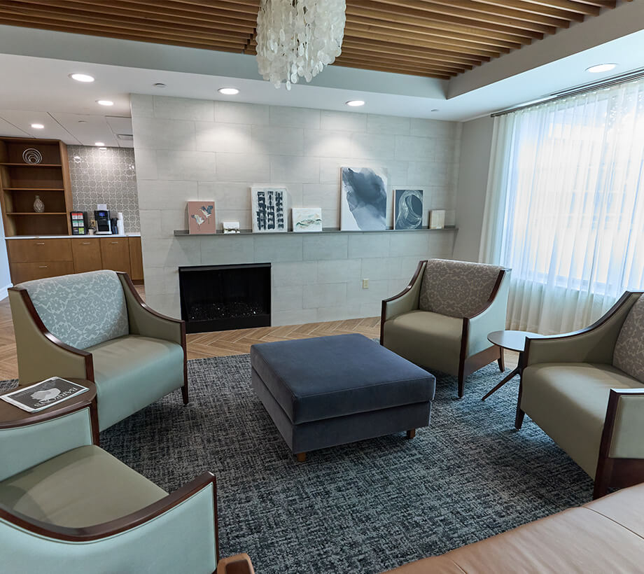 Comfortable lounge area in a senior living community with modern chairs, artwork, and natural light.