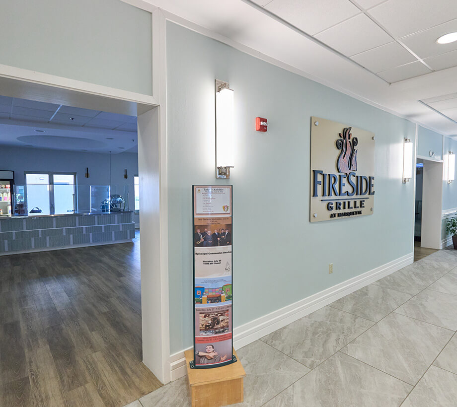 Main hallway with Fireside Grille signage and menu stand in a senior living community.