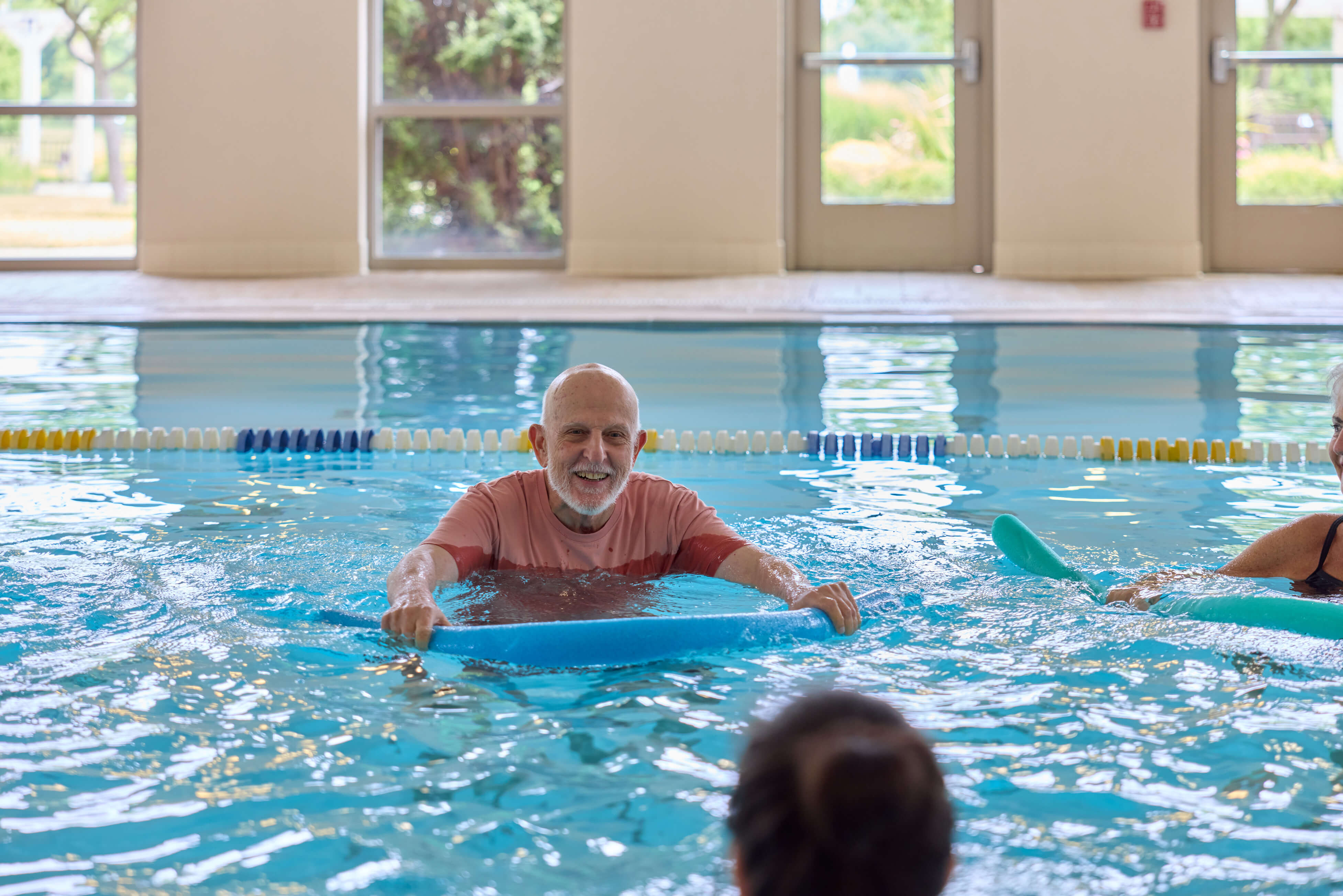 Older adults enjoying swimming in an indoor pool at a senior living community.