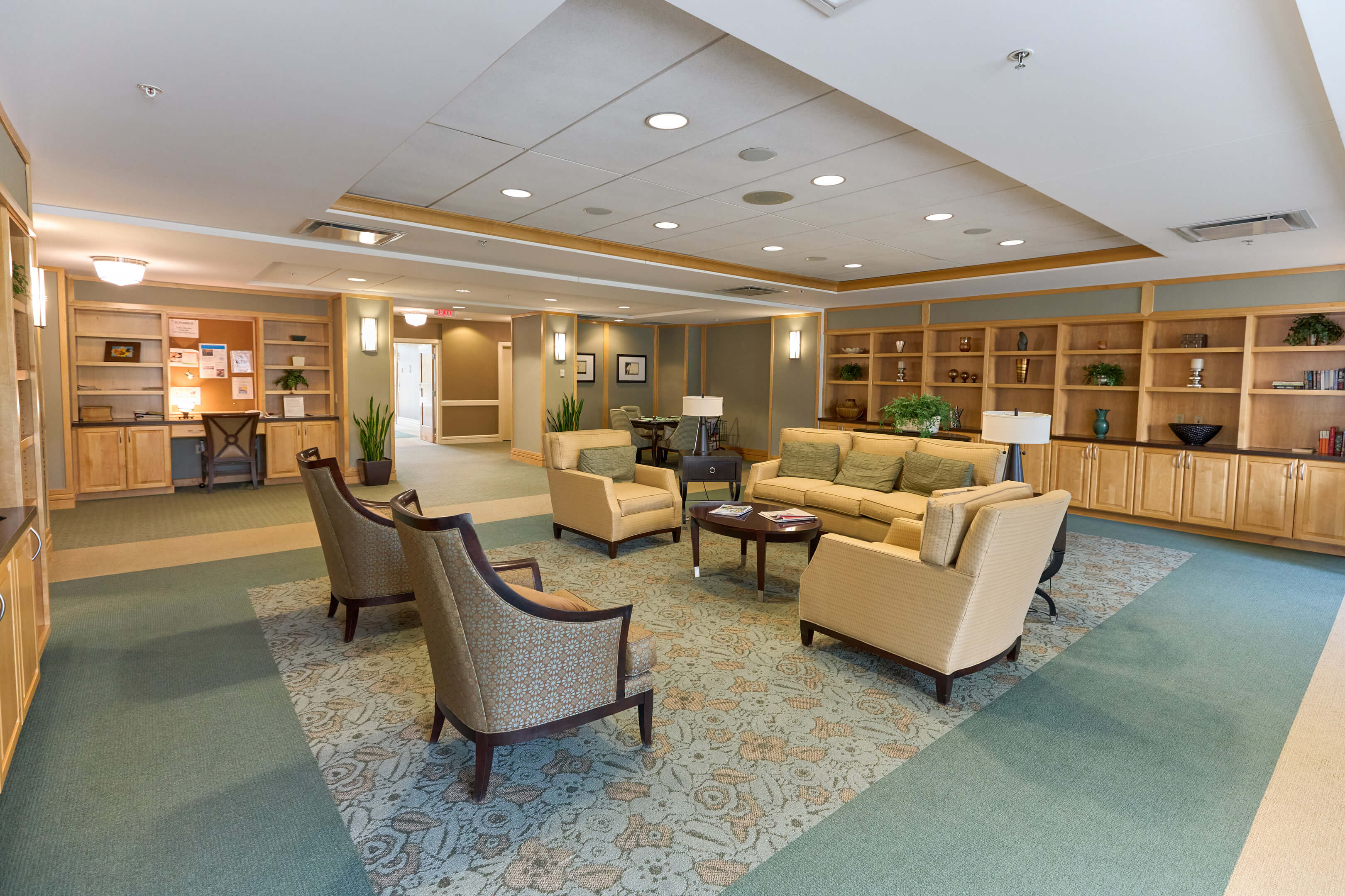 Inviting common area in a senior community with comfortable seating, shelves, and decor.