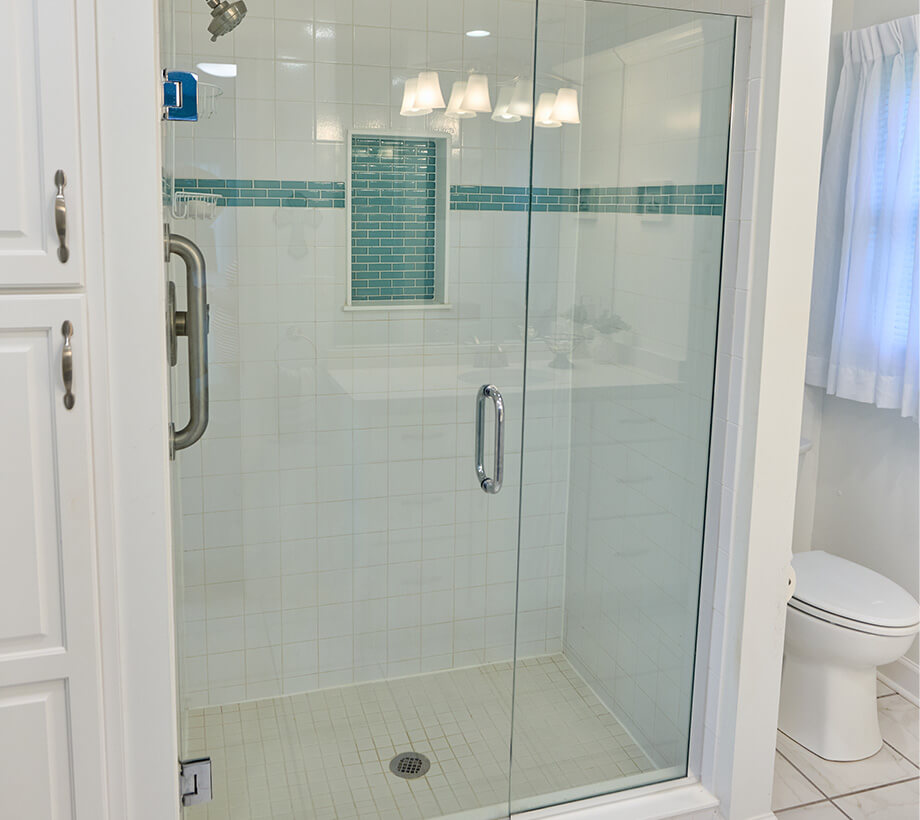 A modern bathroom with a glass-enclosed shower and white and blue tile design.