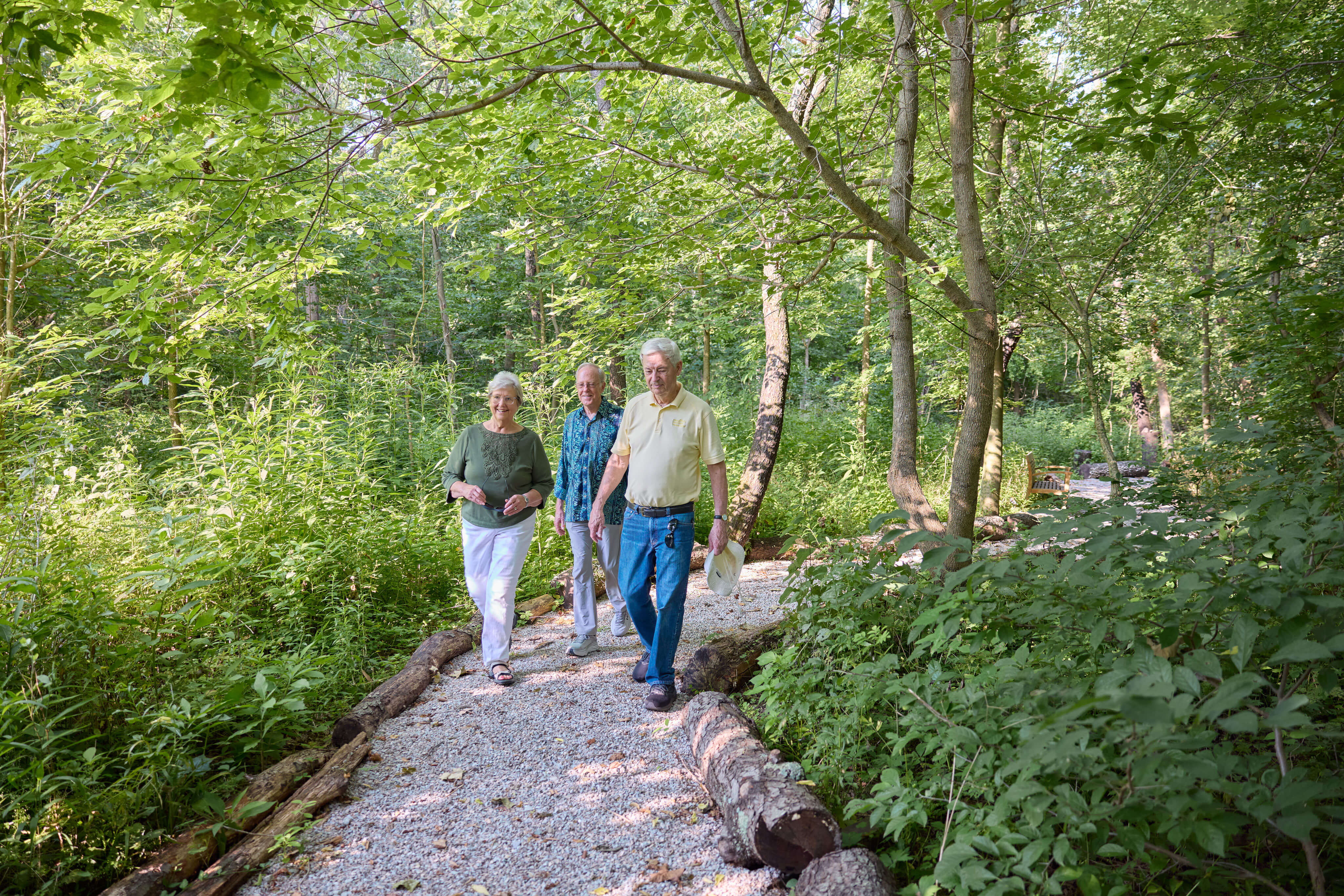 Three seniors walking along a forested path at Marquette.