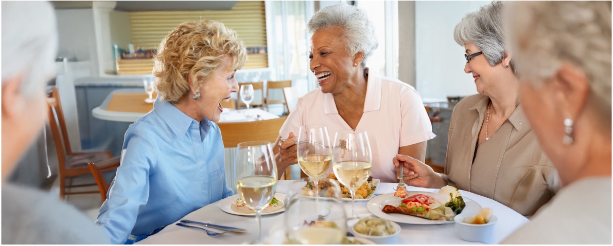 Multiple senior friends laughing at dinner