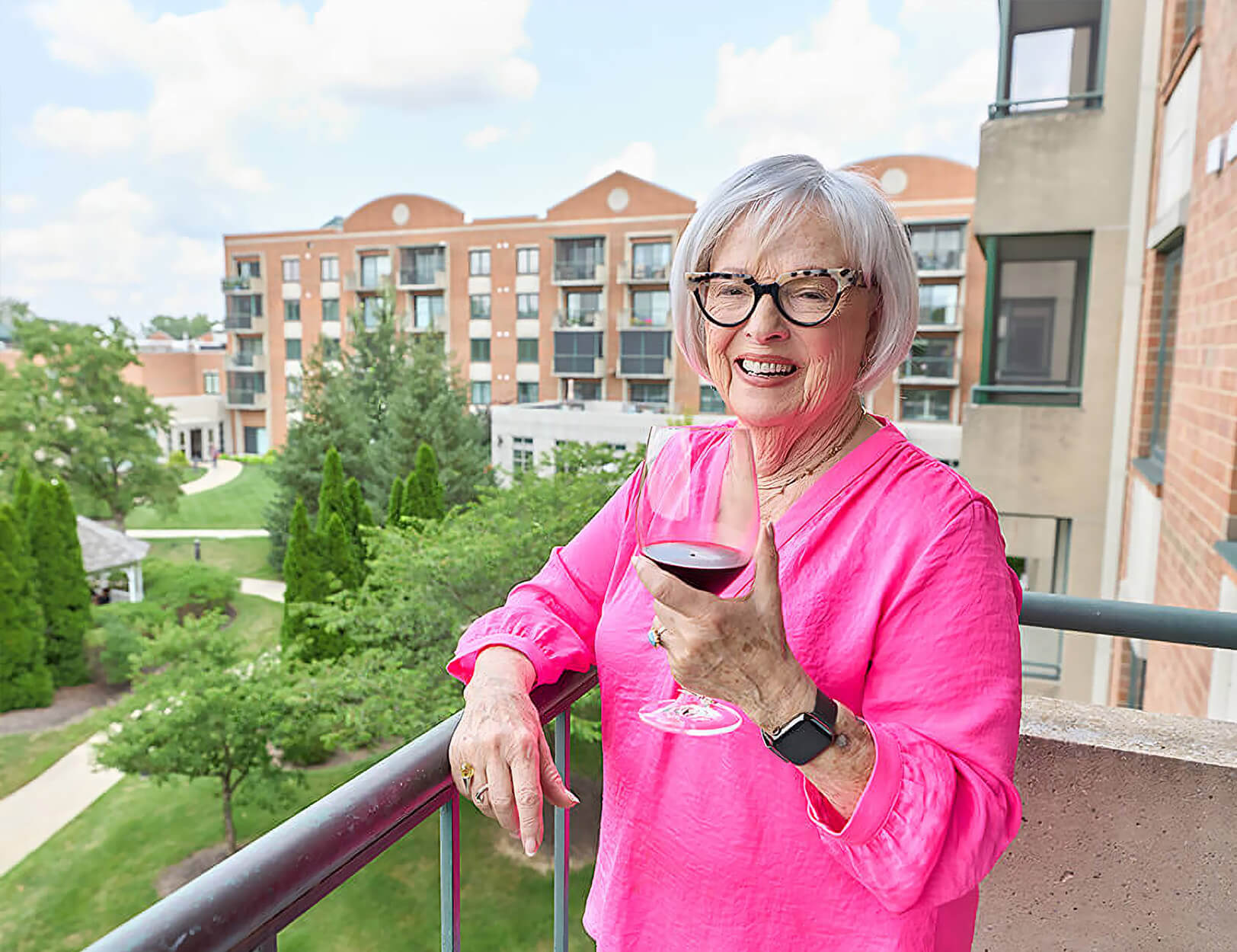 Independent senior on apartment balcony enjoying a glass of wine