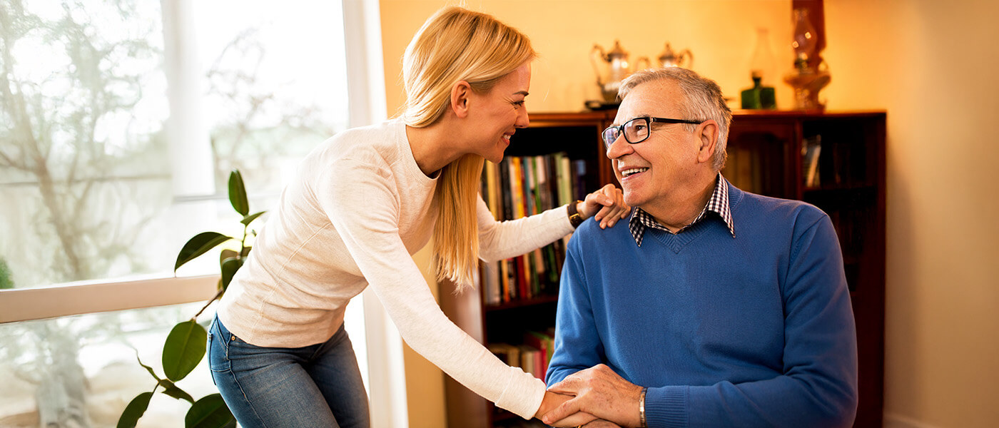 Young woman smiles fondly at senior man as they hold hands