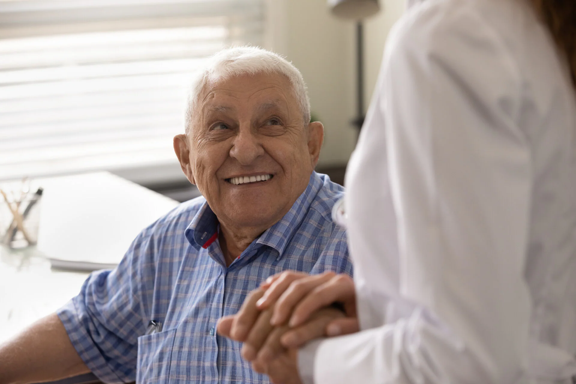 Senior man holding caregivers hand at home