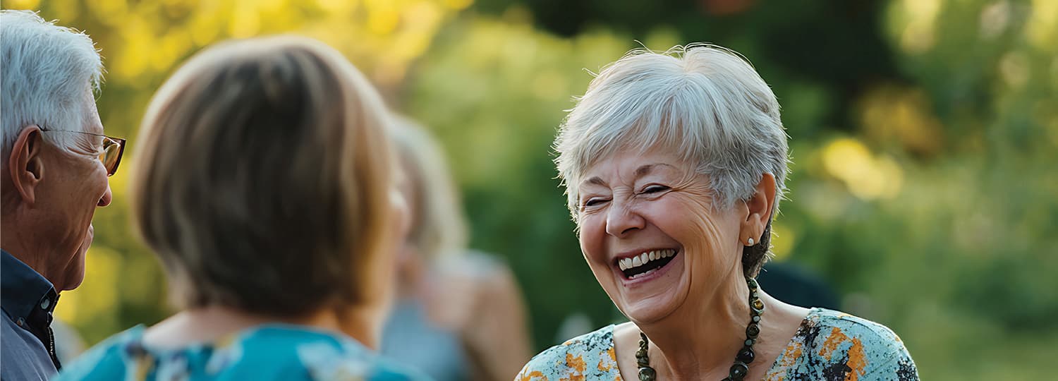 Senior woman laughing with friends during conversation outdoors