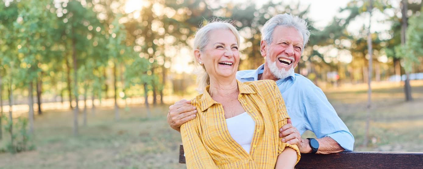 Happy senior couple laughing in a park on a sunny day
