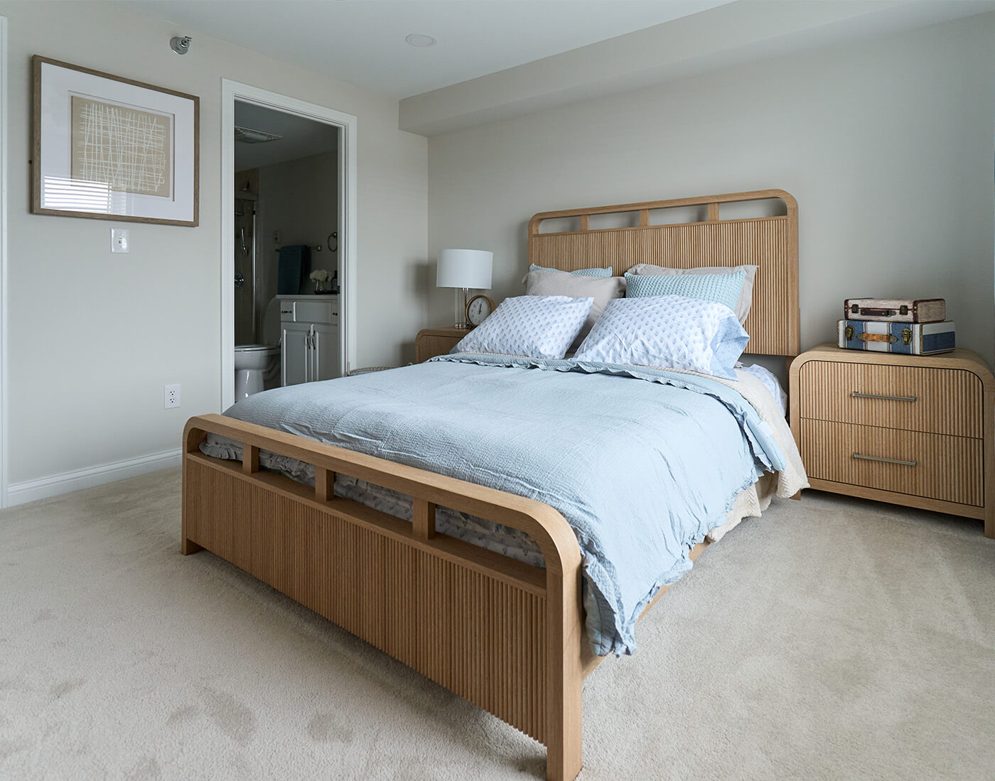Cozy bedroom with wooden bed frame and light blue bedding in a living unit.