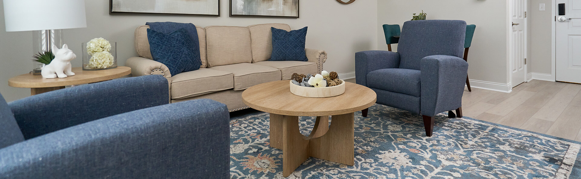 Cozy living area with blue armchairs, beige sofa, and wooden coffee table.