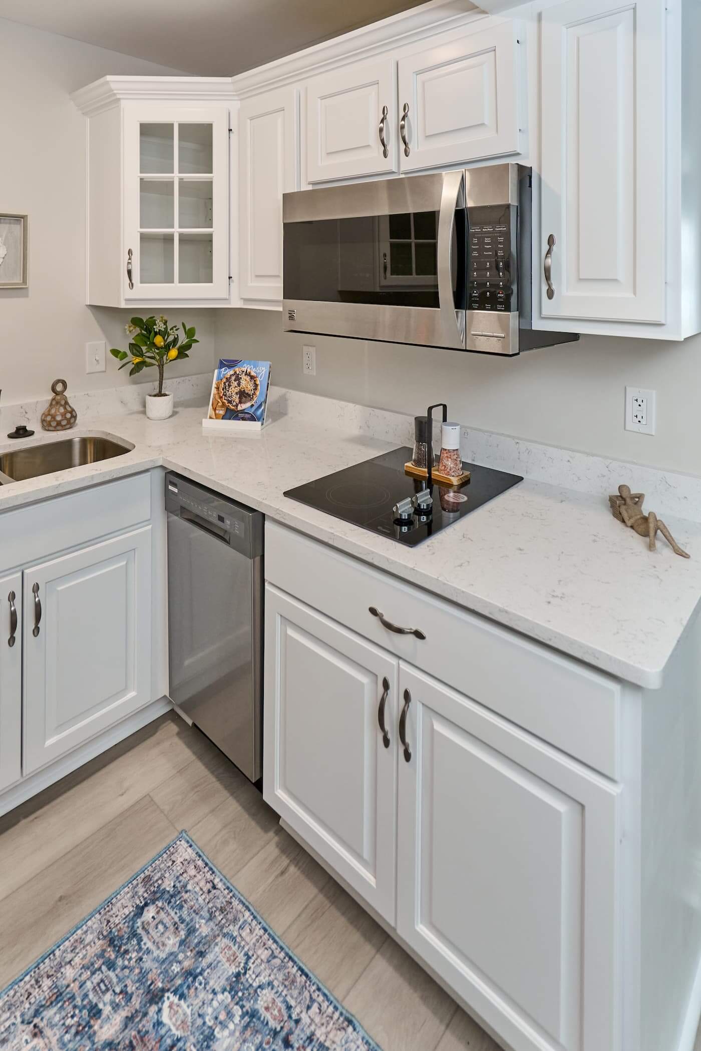 Modern white kitchen with microwave, stove, and potted plant on the counter.