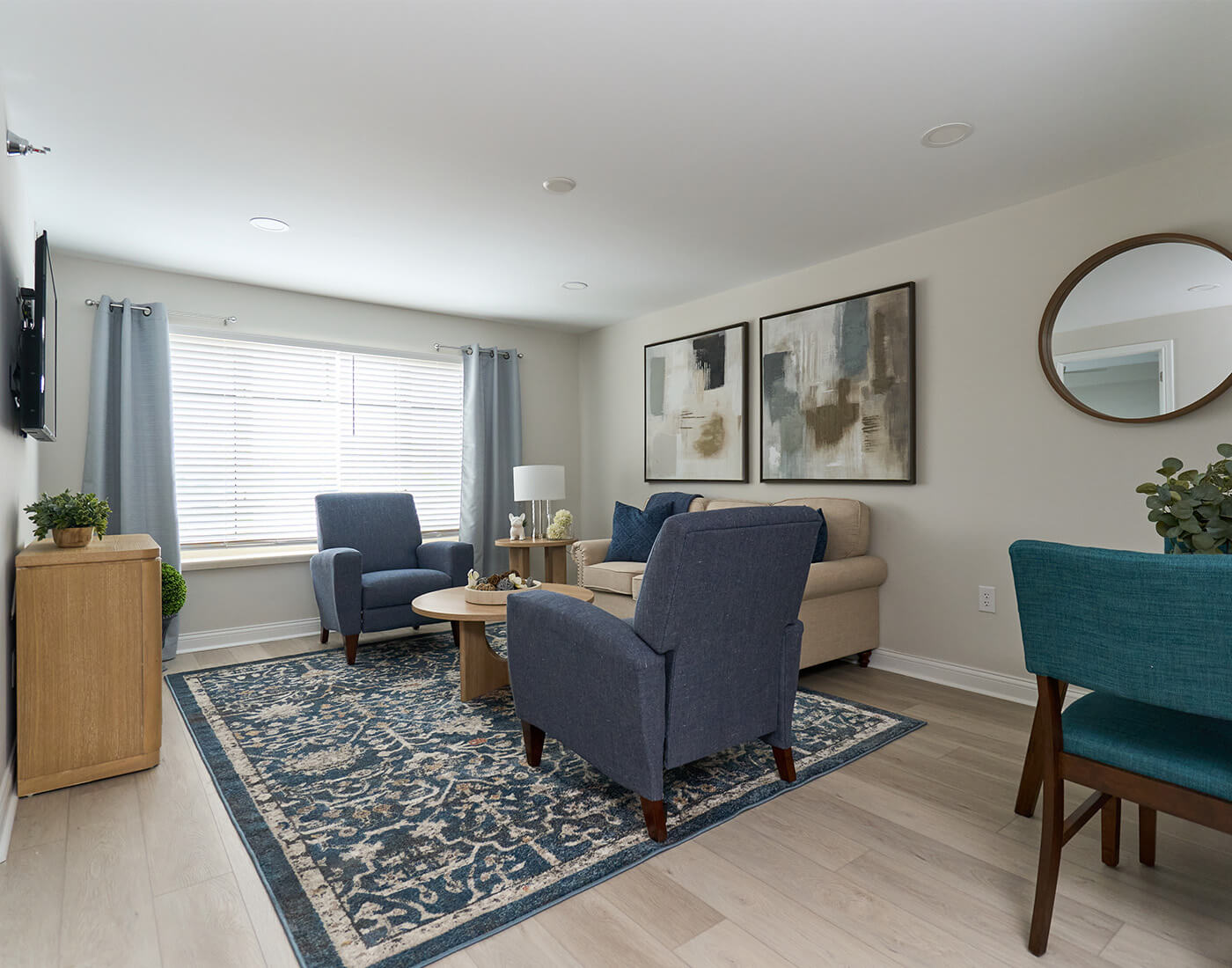 Cozy living room with blue armchairs, beige sofa, and abstract art on walls.