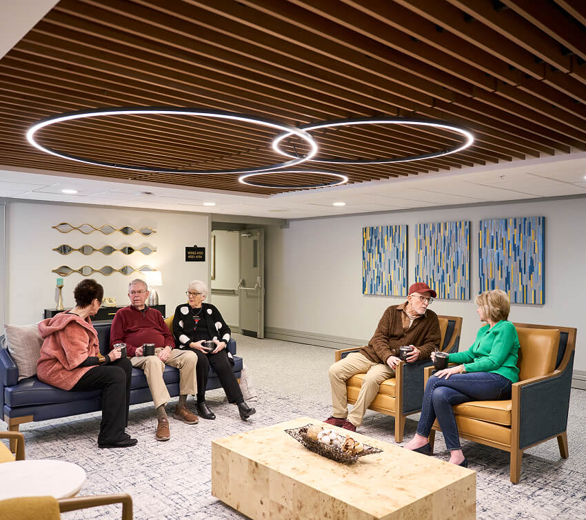 Residents enjoying conversation in a modern common area with stylish ceiling lights.