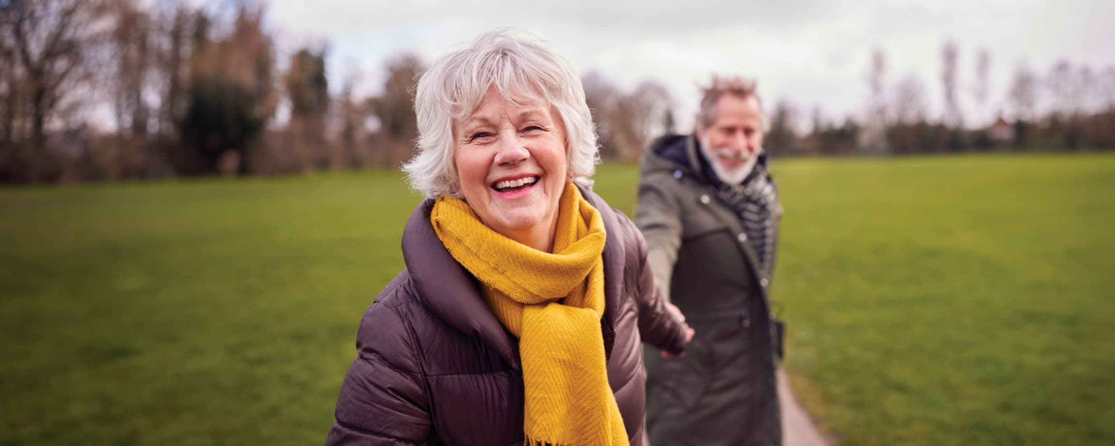 Senior woman and man smiling in open field