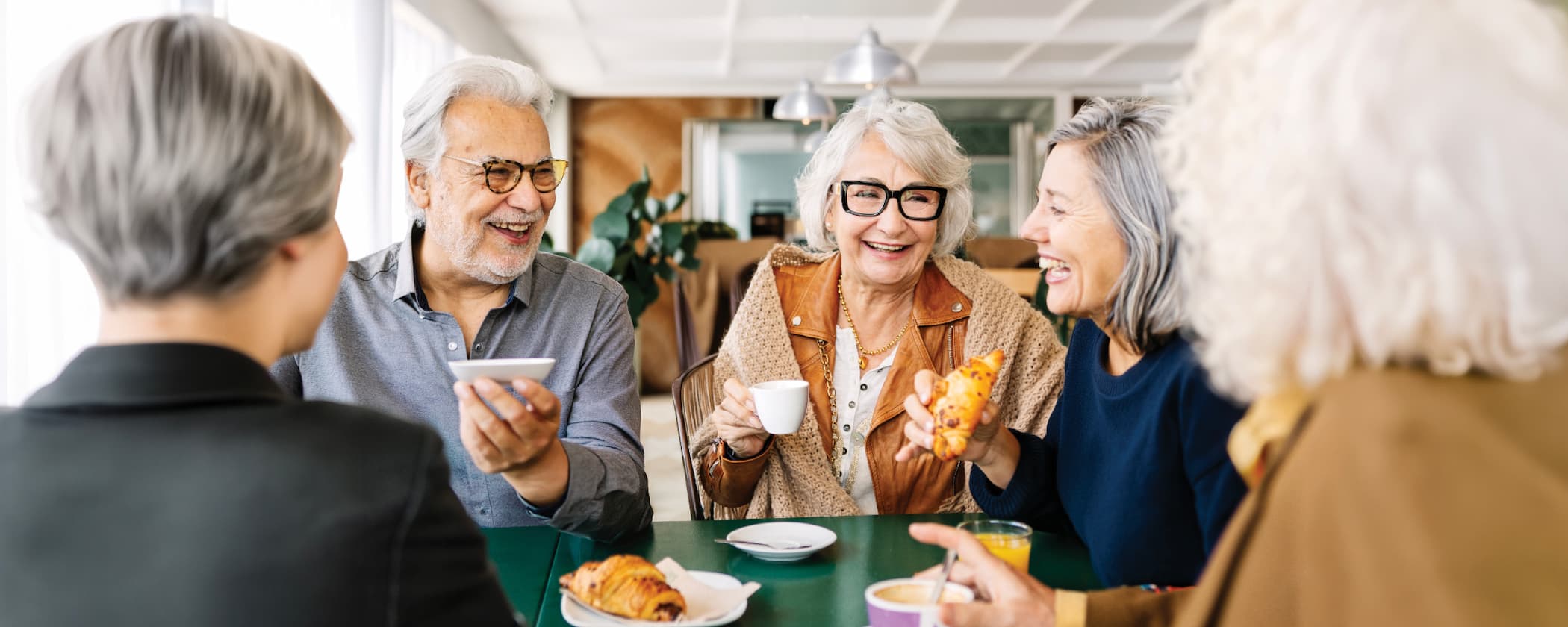 Senior friends laughing and enjoying breakfast